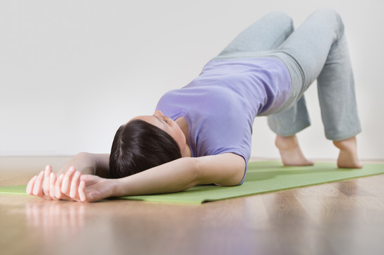 Portrait of healthy young woman practising yoga exercise on mat